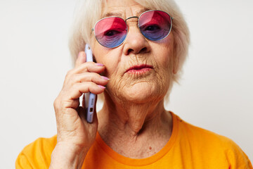 smiling elderly woman in casual t-shirt sunglasses talking on the phone close-up emotions