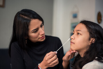 Mother doing auto test antigen nasal swab test stick to detect possible covid.