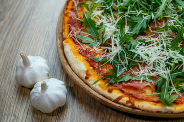 pizza with ham, arugula, tomato sauce and shredded mozzarella