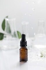 Glass dropper bottle with essential oil on wet table under falling down drops