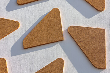 Close-up of a street   white wall with raised  orange details. Tile pattern