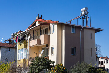 Fototapeta na wymiar Colorful Turkish house with barrels of hot water on the roof and solar panels