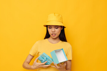 Charming young Asian woman blue gift box holiday birthday yellow background unaltered