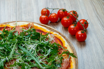 pizza with ham, arugula, tomato sauce and shredded mozzarella