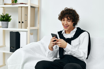 curly guy in the room on the couch with the phone online learning communication