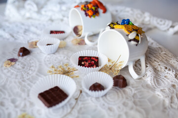 White mugs and saucers with handmade chocolate on a lace background