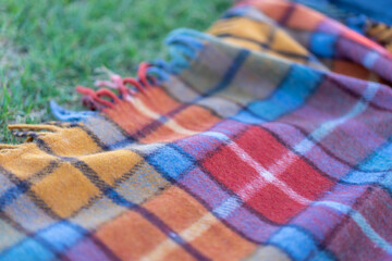 Picnic blanket lies on the grass on a sunny day. Wool checkered picnic rug Blanket