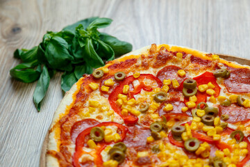 pizza with mozzarella, green olive, salami, corn and red pepper