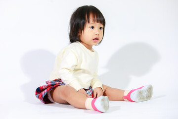 Naklejka premium Studio shot of little cute short black hair Asian baby girl daughter model in casual plaid skirt sitting and smiling on white background