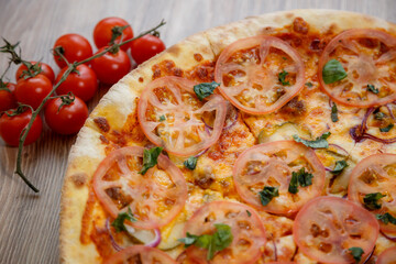 pizza with meat, mozzarella, tomatoes, spinach and tomato sauce