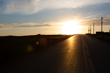 An asphalt road stretching into the distance at sunset