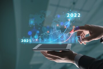 Businessman hand holding tablet showing graph economic growth target success. Plan business growth in year 2022 concept.