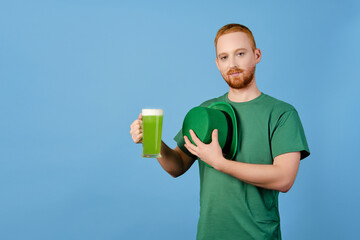Happy St. Patrick's Day. A red-haired guy in a green hat raises his hands up, a glass of green beer