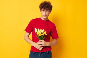 portrait of a young curly man in a red t-shirt a bouquet of flowers holiday gift monochrome shot