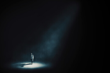 Obraz na płótnie Canvas Businesswoman walking under light in dark room