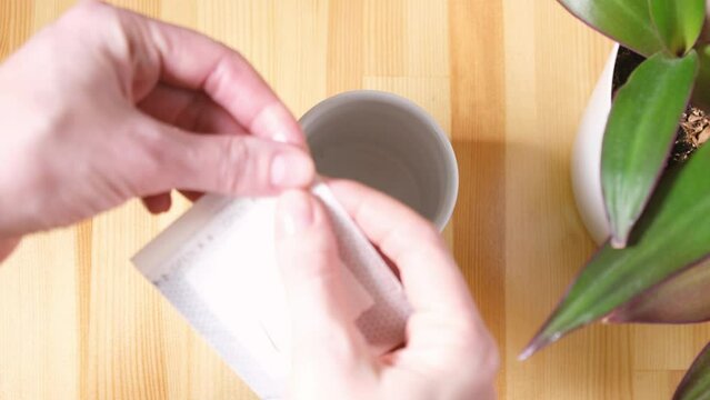 Pouring hot water through a fancy paper bag for coffee drops into a cup on a wooden table. Preparation of freshly brewed coffee at home. 4K UHD. High-quality 4k frames 