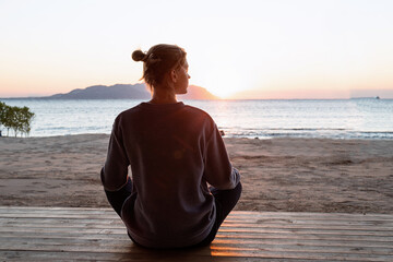 Fototapeta premium Young healthy woman practicing yoga on the beach at sunrise