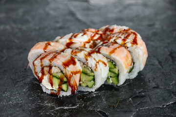 Philadelphia sushi rolls with eel on a black background poured with sauce
