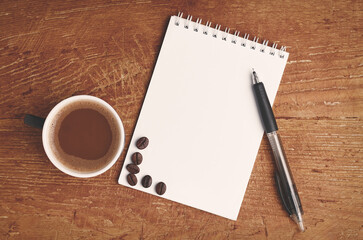 white sheet for writing and coffee on wooden table