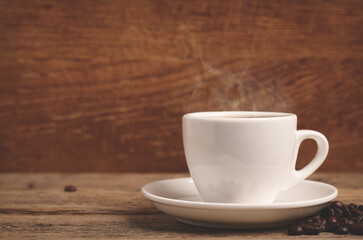 White cup with hot coffee on wooden table