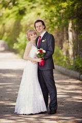 Wedding day of Young couple in a summer garden. Bride and Groom tender holding each other. Blonde woman and brown-haired man. Wedding family outdoor walk. Love and tenderness. Newlyweds srarts life