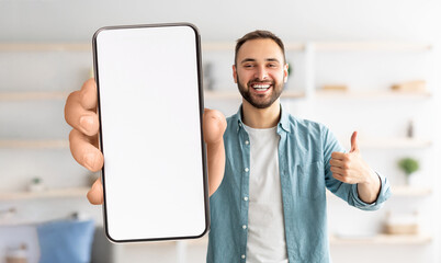 Cheerful guy showing white empty smartphone screen, closeup
