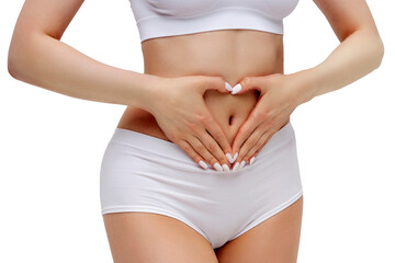 Slim woman in white underwear forming a heart symbol with her hands on her belly, isolated on white background