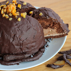 Cut Italian  Zuccotto cake made with chocolate sponge cake ,chocolate and orange cream on plate on wooden table