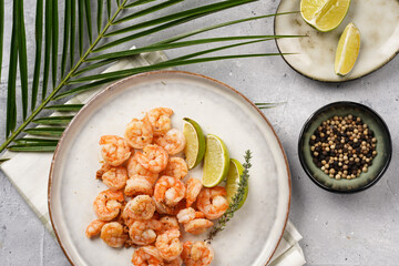 Grilled shrimps or tiger prawns served with lime, garlic and fresh herbs on scandi round plate on concrete surface. Pescatarian protein nutrition