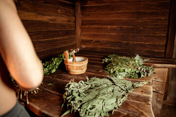 Bath accessories: basin, broom, ladle, on the background of a wooden bath