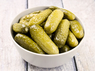 Pickled cucumbers in a bowl on a wooden rustic table