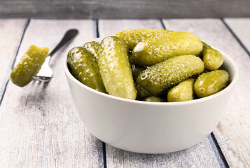 Pickled cucumbers in a bowl on a wooden rustic table