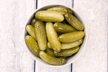 Pickled cucumbers in a bowl on a wooden rustic table