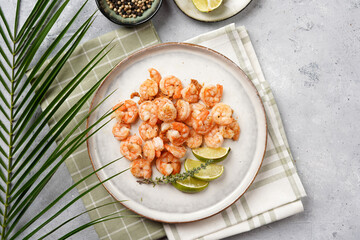 Grilled shrimps or tiger prawns served with lime, garlic and fresh herbs on scandi round plate on concrete surface. Pescatarian protein nutrition