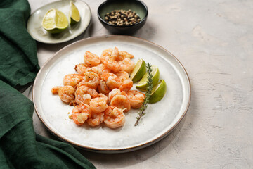 Grilled shrimps or tiger prawns served with lime, garlic and fresh herbs on scandi round plate on concrete surface. Pescatarian protein nutrition