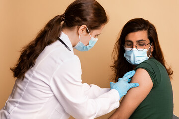 Woman doctor making intramuscular injection for arab guy at clinic