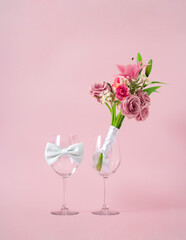 Creative wedding glasses concept the bride with wedding bouquet made of fresh flowers and groom with tie. Pastel pink background.