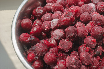 Freshly frozen red cherry berries in a metal bowl.