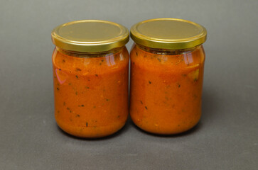 Hippophae jam in a glass jar with the lid on gray background.
