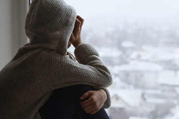 Depressed Upset sad teen girl looks out the window back to the camera. Difficult teenage...