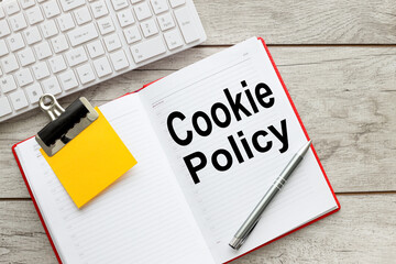 COOKIE POLICY . text on an open red notepad with a sticker on a wooden background