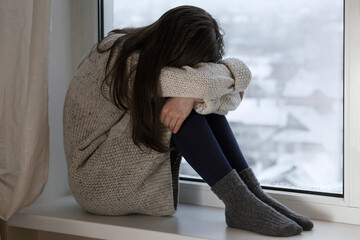 Stress, Depression. Lonely teen girl feeling depressed and stressed sitting by the window, Negative...