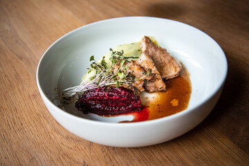 Delicious roasted pork filet cooked with smashed potatoes and smashed beetroots served in white plate.