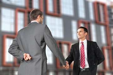 Handsome young businessman in formal suit talking with partner outdoors in the city