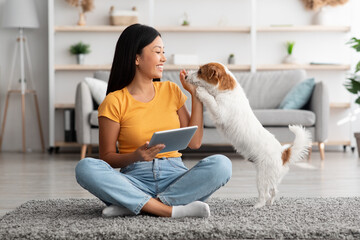 Asian woman and cute dog having fun together at home