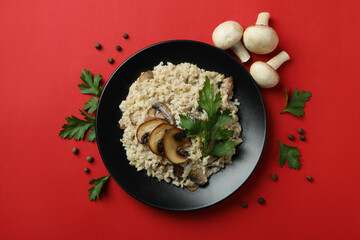 Concept of tasty food with risotto with mushrooms on red background