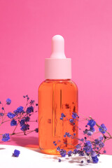 Glass cosmetic bottle with oil or serum for skin care on pink background. Shadows Natural skin care concept.