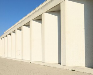 Modern white stone colonnade with tiled pavement in front. Background for copy space