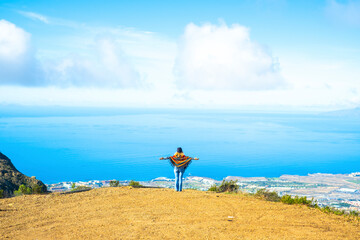 Tourist and freedom lifestyle people travel concept. Woman viewed from back opening arms to enjoy...