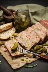 Sliced Traditional French terrine covered with bacon on dark wooden background